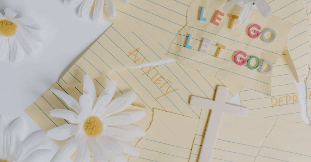Flat lay of daisies, torn yellow notepaper with the words "Anxiety" and "Depression," a small white wooden cross, and colorful letters spelling "Let go, let God."