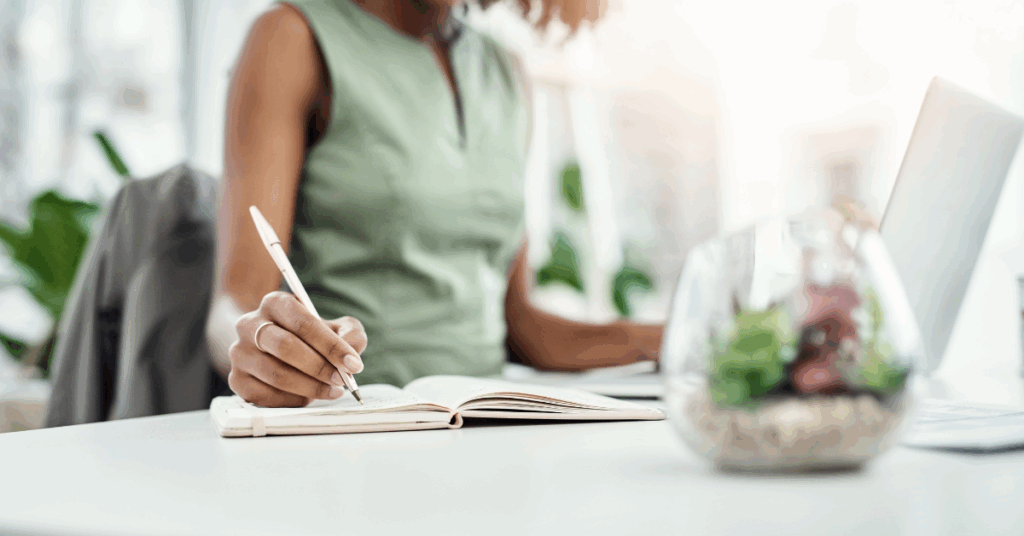 a woman doing research on a computer, taking notes.