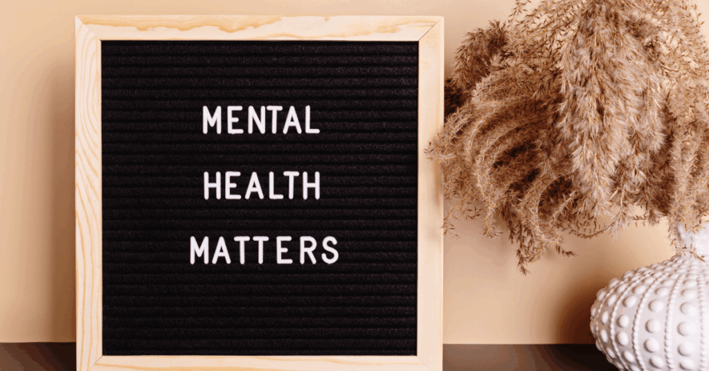 Neutral tone wall with vase with pampas in it and a letterboard sign that says Mental Health Matters
