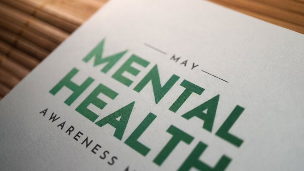 Mental Health Awareness Month: Why Awareness Alone Isn’t Enough - May Mental Health Awareness poster with bold green text on white paper.