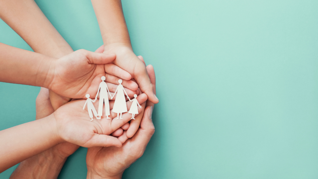 Multiple hands form a circle around a white paper cutout of a family holding hands, symbolizing support and togetherness with a teal background.